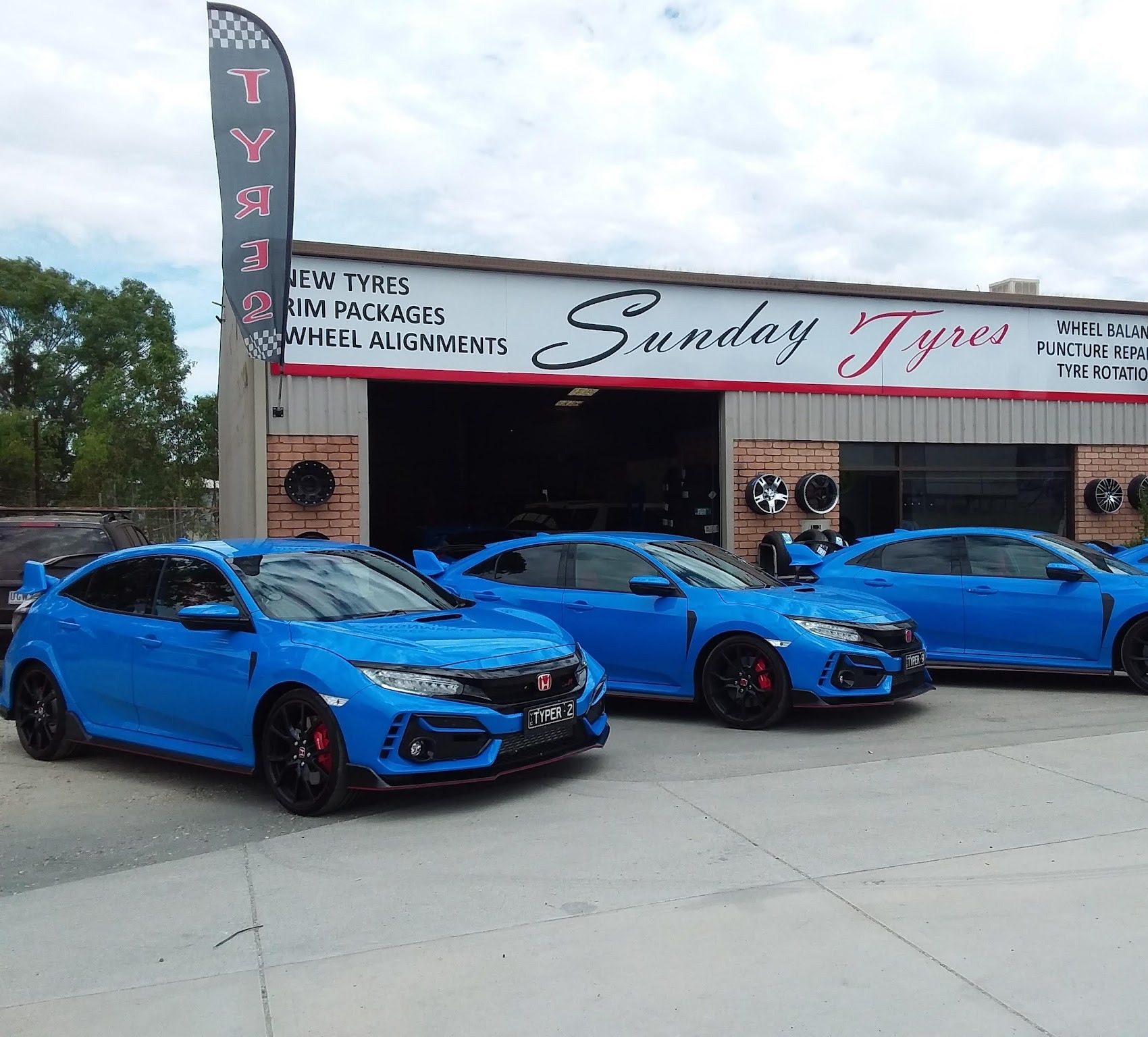 Sunday Tyres shopfront with checkered flags and a line of Honda Civic Type Rs