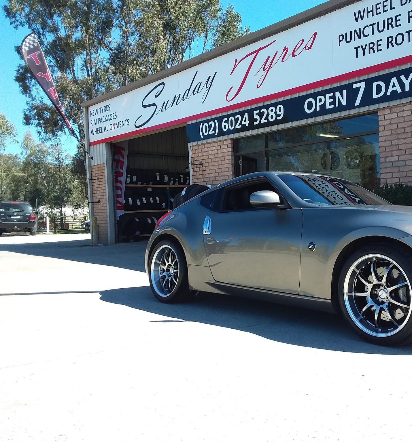 A Nissan 370Z on new alloy wheels parked outside the Sunday Tyres shopfront
