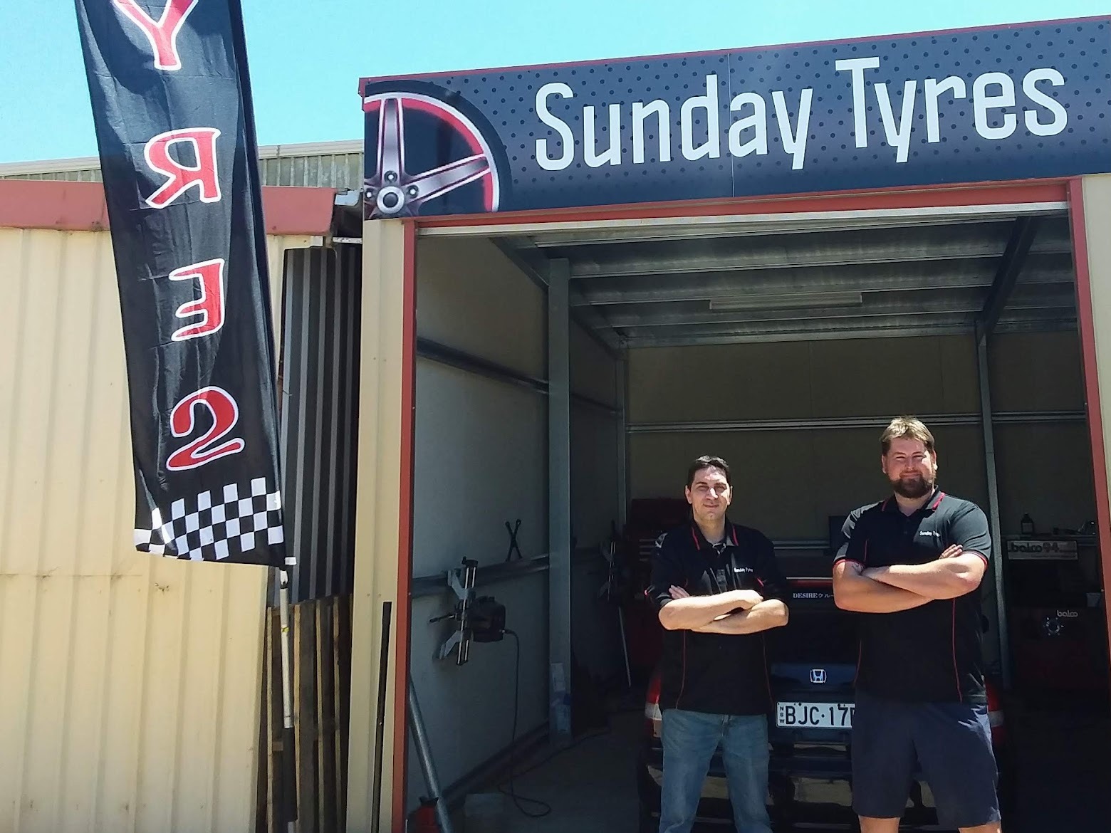 Two of the Sunday Tyres team in branded shirts outside the workshop